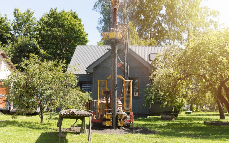 Brunne-Baumaschine steht mitten im Garten zwischen Bäumen bereit zum Bohren