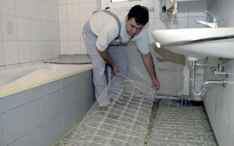 Handwerker versteilt Fußbodenheizelementen auf dem Boden