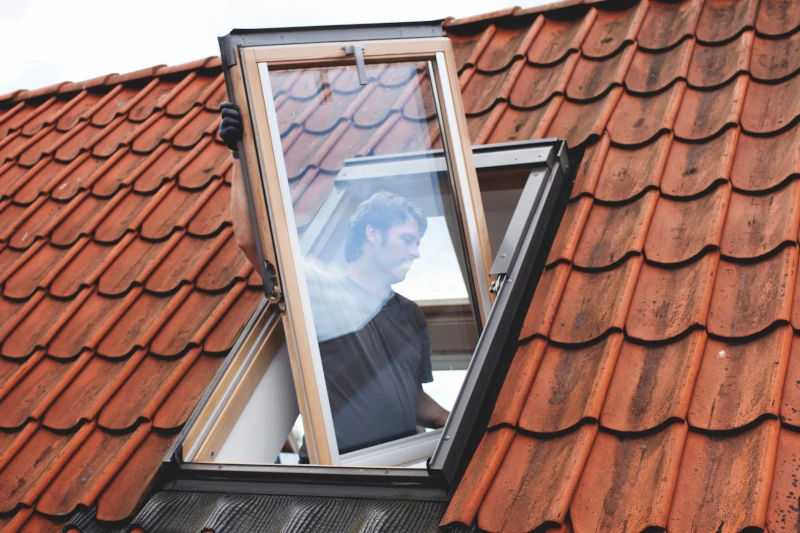Mann baut neues Dachfenster ein