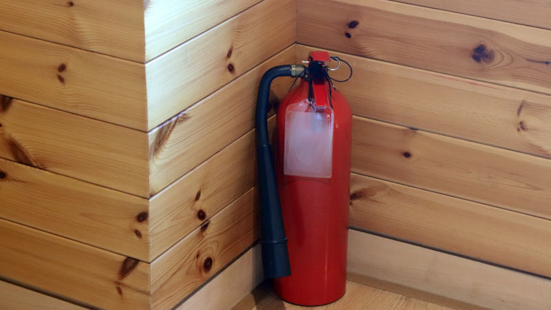 ein Feuerlöscher hängt in der Halterung in einem Holzhaus