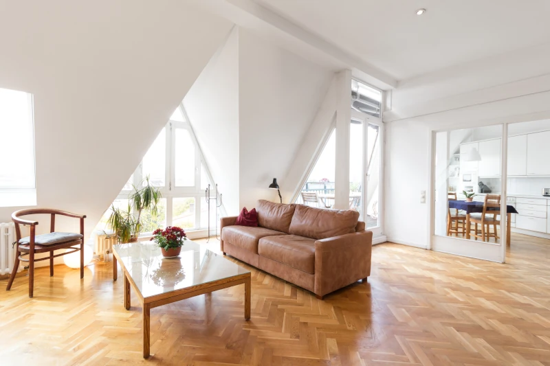 Wohnzimmer mit vielen Fensternischen, älteren Möbeln und Laminatboden