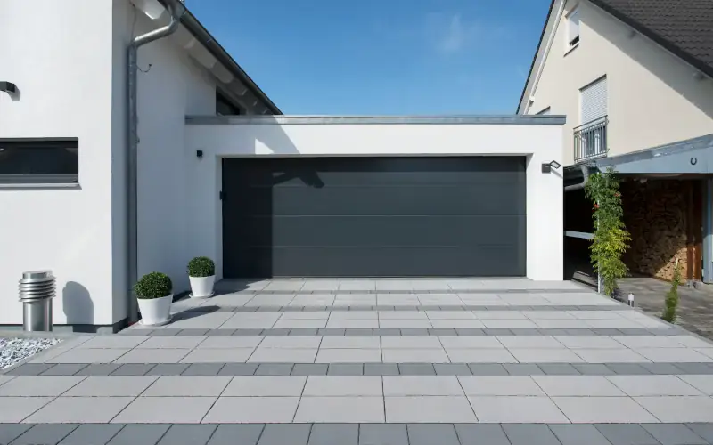 Grau gepflasterter Weg vor einer Garage