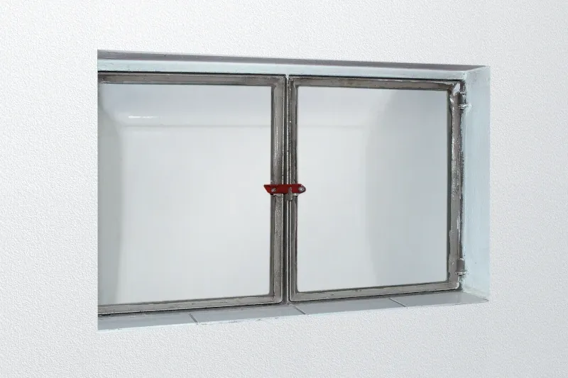 Ein weißes, veraltetes Kellerfenster ist zu sehen.