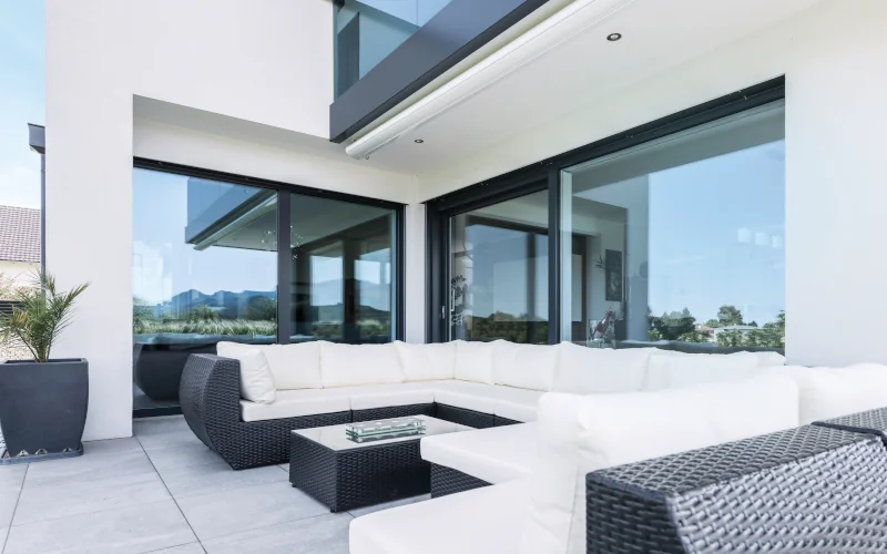 modernes weißes Haus mit Terrassenbereich mit großen Fenstern und einer großen Sitzlounge