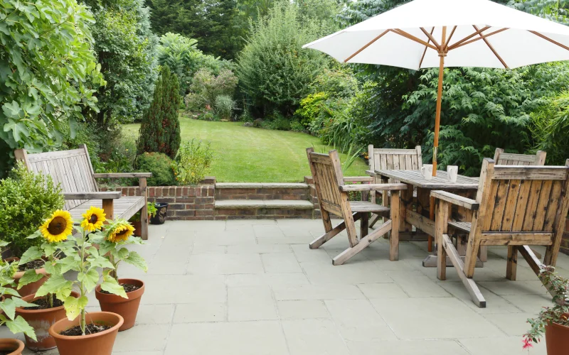 Terrasse mit Holzgartenmöbeln und einem Garten dahinter