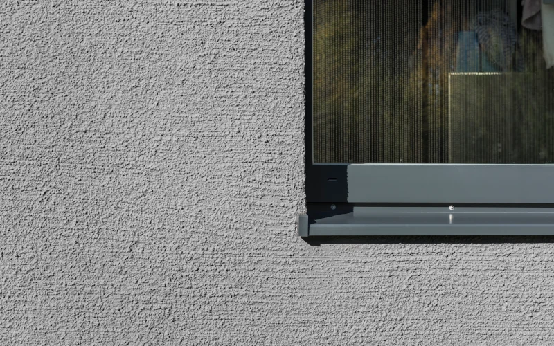 Putz an Hausfassade, daneben ein Fenster