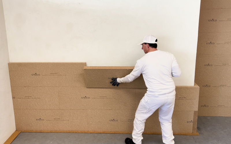 Handwerker bringt Holzfaser-Dämmplatten an einer Wand an