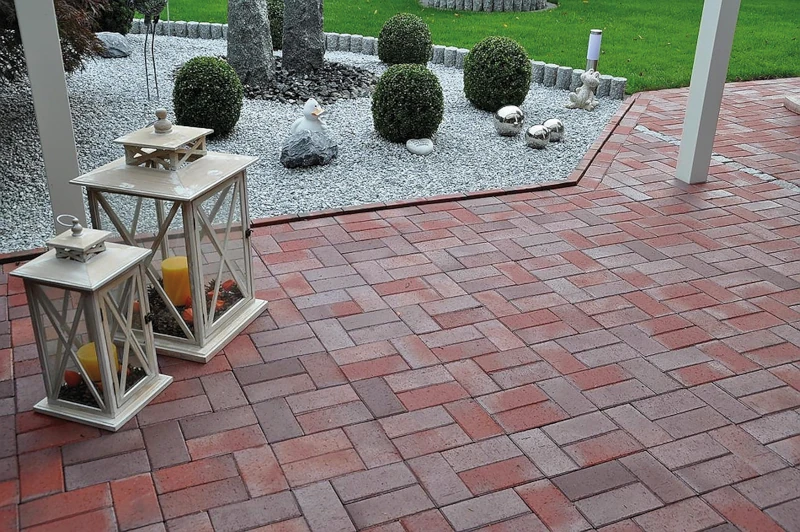 Terrasse mit rötlich-schattierten Pflastersteinen und Dekoration.