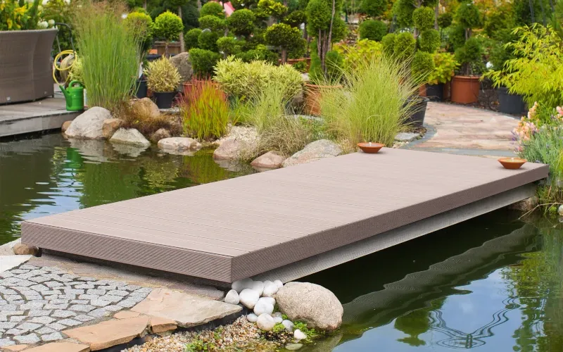 Teich im Garten und in der Mitte ein Sockel aus Dielen zum Sitzen