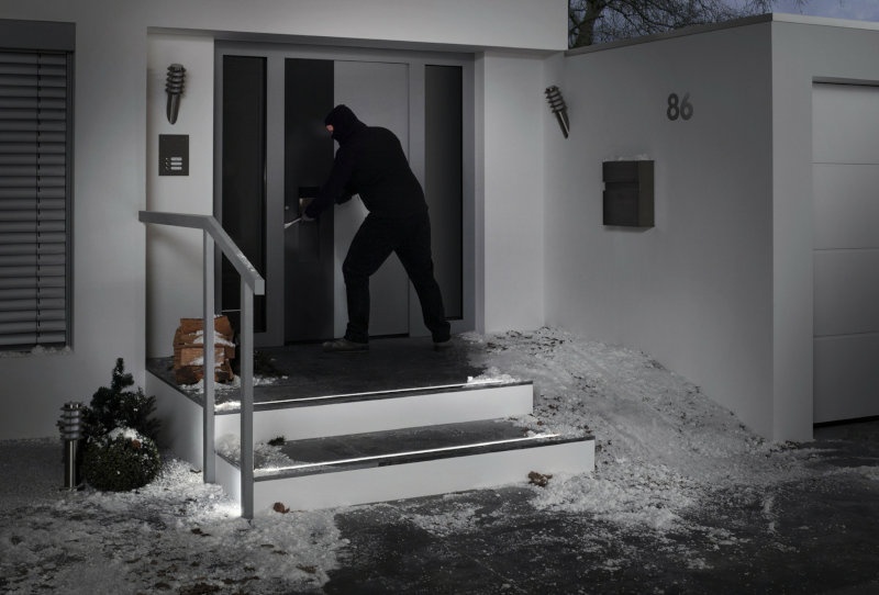 Ein Einbrecher versucht im Dunkeln eine Haustür aufzuhebeln