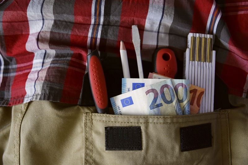 Handwerker hat Werkzeug und Geld in der Tasche
