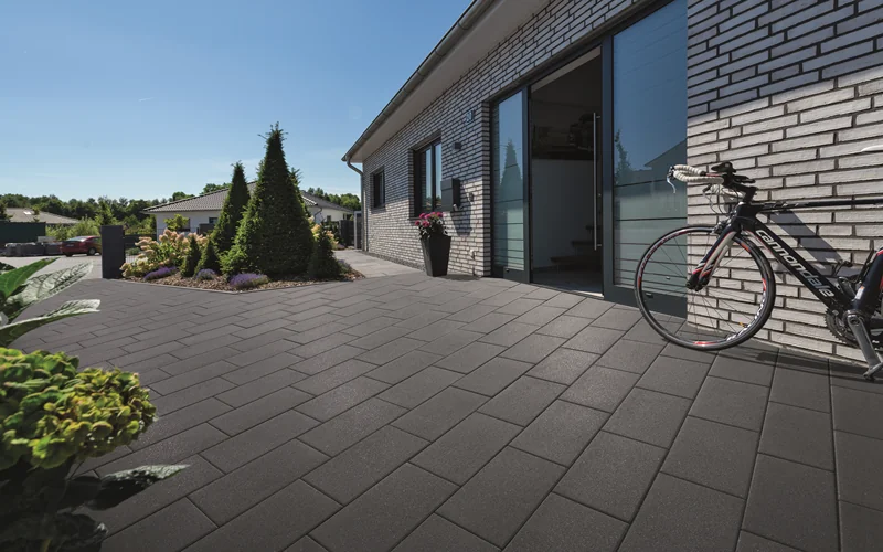 anthrazit gepflasterte Fläche vor Hauseingang und Fahrrad lehnt am Haus