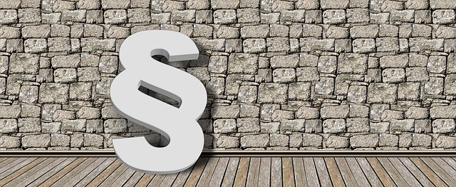 Paragraphensymbol vor einer Steinwand und Holzboden.