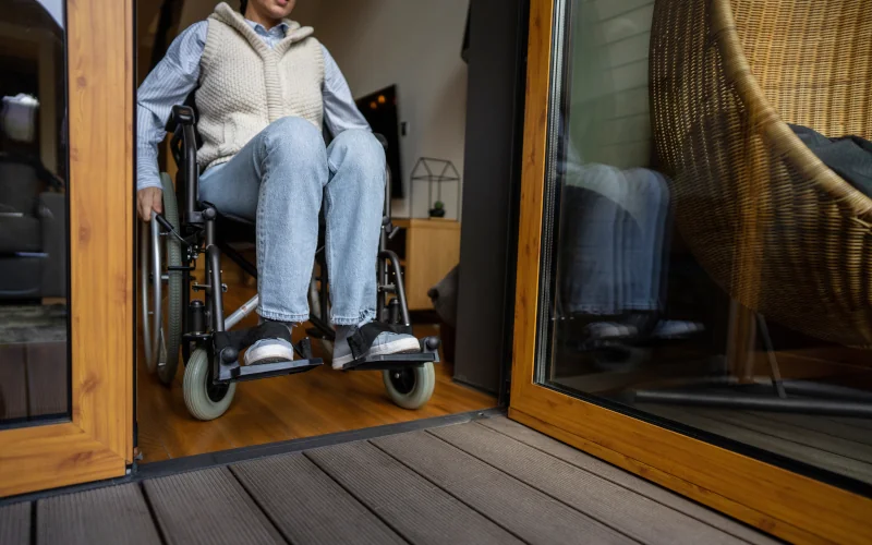 Frau mit Rollstuhl die auf eine Terrasse rausfährst