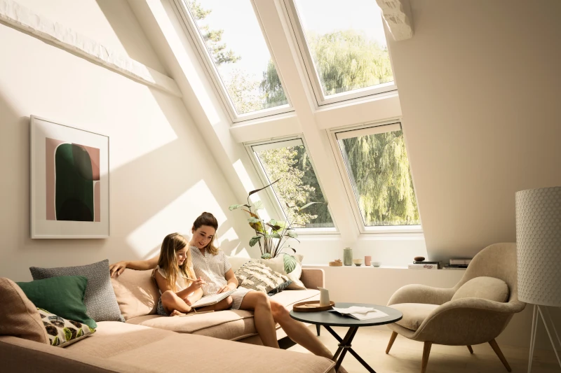 Frau und Kind sitzen im Wohnzimmer unter Dachfenster