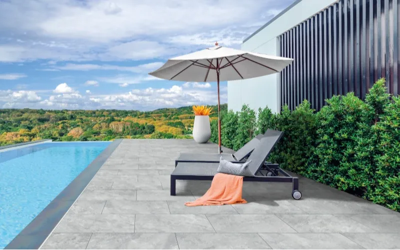 Terrasse mit hellgrauen Platten neben einem Pool