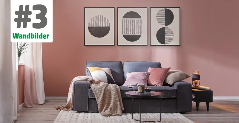 Sofa vor einer pinken Wand mit vielen Decken und Kissen