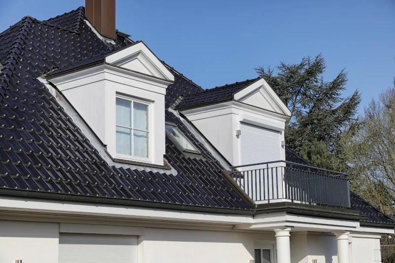 weißes modernes Wohnhaus mit schwarzem Dach und kleinem Balkon
