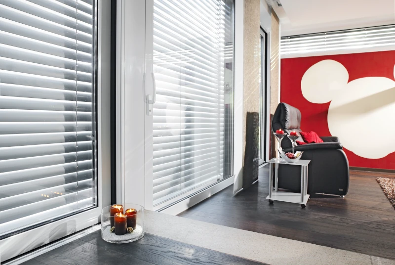 Ein bodentiefes Fenster ist durch einen Sonnen- und Sichtschutz geschützt.