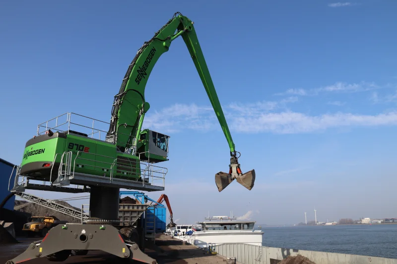 Großer grüner Hafenkran am Wasser im Einsatz.