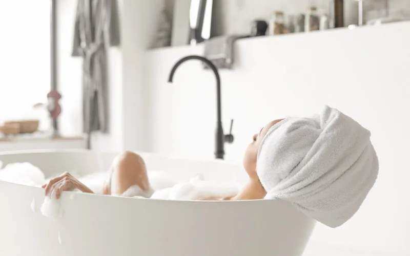 Frau liegt in einer freistehenden Badewanne