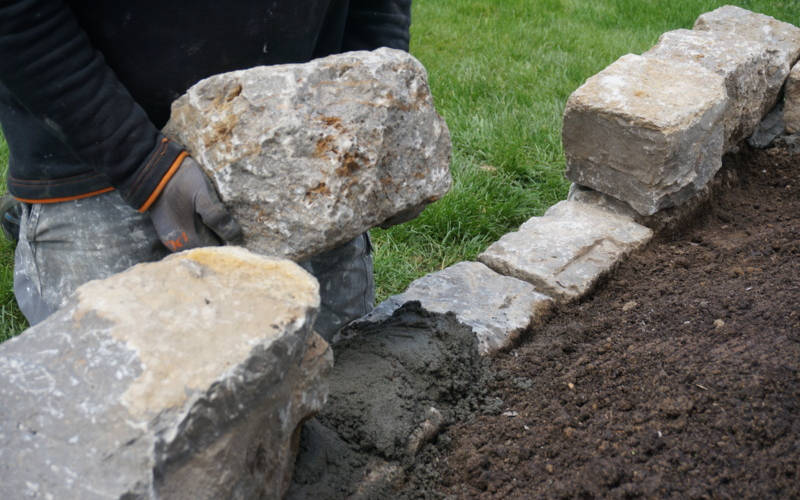 Steine werden in Naturmauer eingesetzt