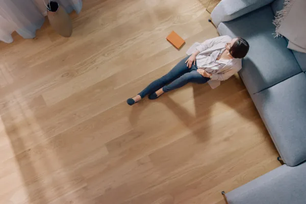 eine Frau sitzt auf dem Boden angelehnt an ein Sofa