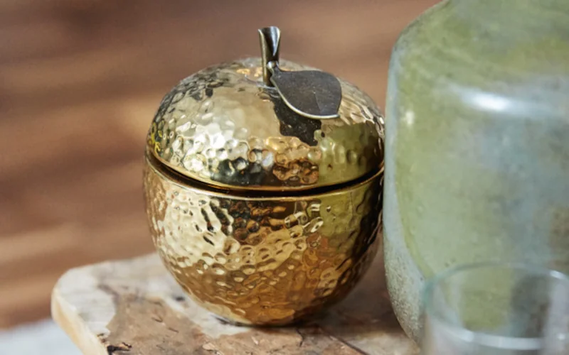 goldschimmernder Deko-Apfel auf einem Beistelltisch
