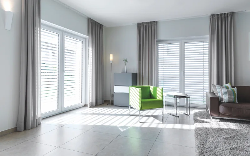 Wohnraum mit minimalistischer Einrichtung Blick aus Fenstern heraus mit Alu-Jalousien davor