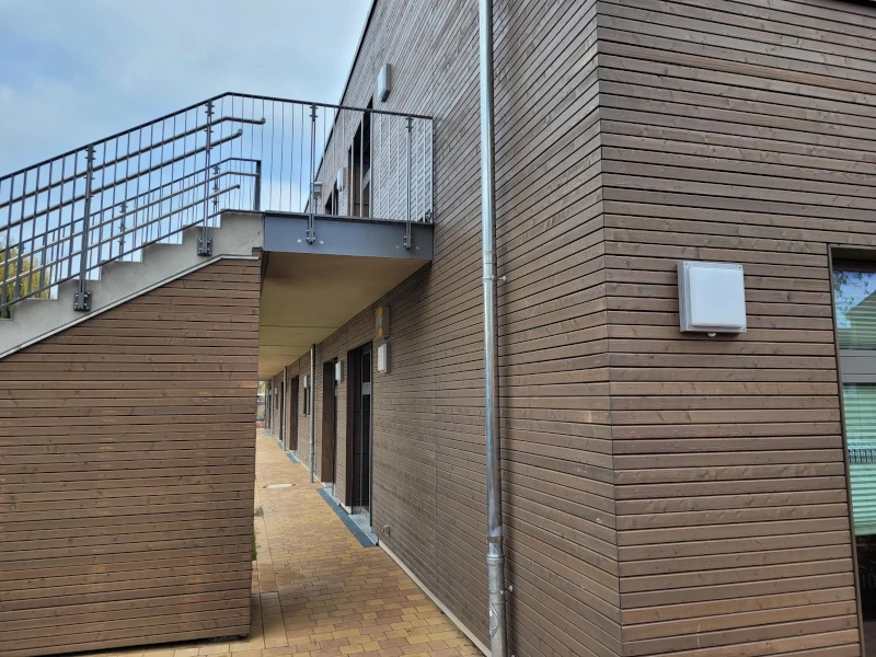 Gebäude mit einer Holzfassade und einem Treppengeländer.
