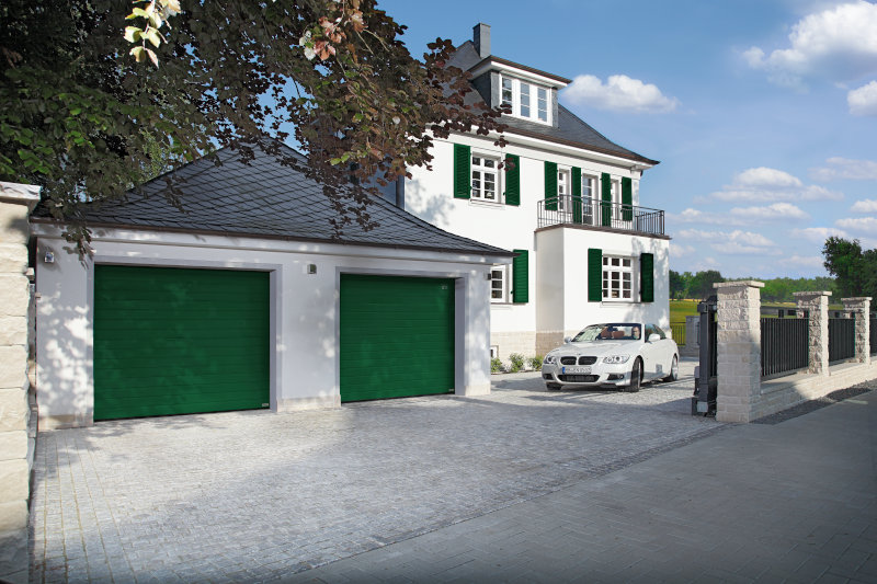 Elegantes Haus mit grünen Garagentoren und geparktem Auto.