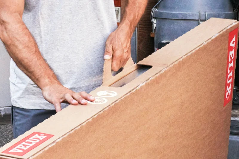 Mann transportiert Produkt von Velux in einem Karton