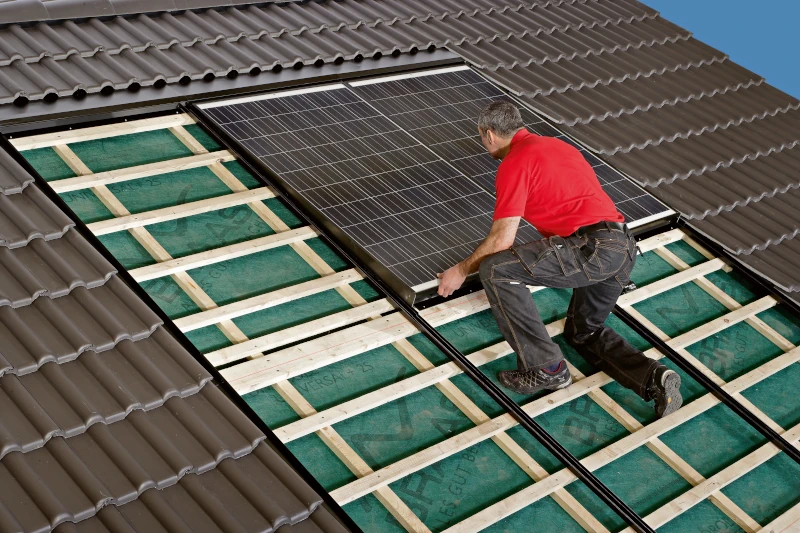 Mann baut Photovoltaikanlage auf Dach ein