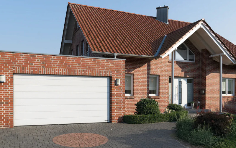 Wohnhaus mit roter Klinkerfassade, rotem Steildach und anliegender Garage