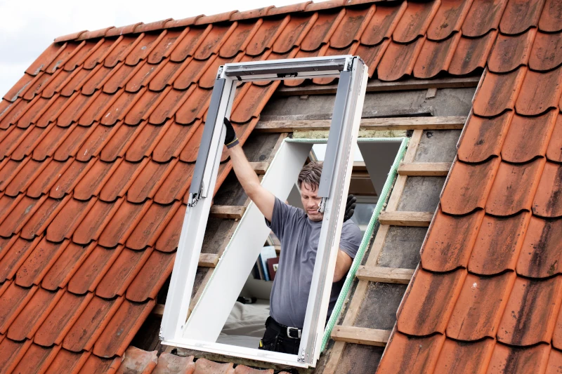 Mann tauscht altes Dachfenster aus