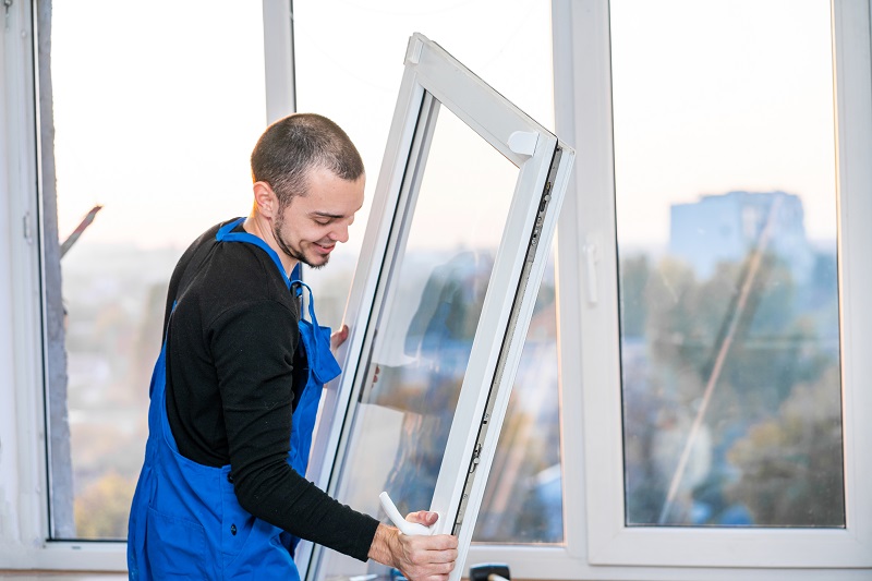Arbeiter in Schutzkleidung tauscht Fenster aus