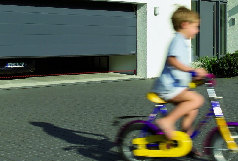 Ein Kind fährt auf einem Fahrrad eine Auffahrt vor der Garage hin und her