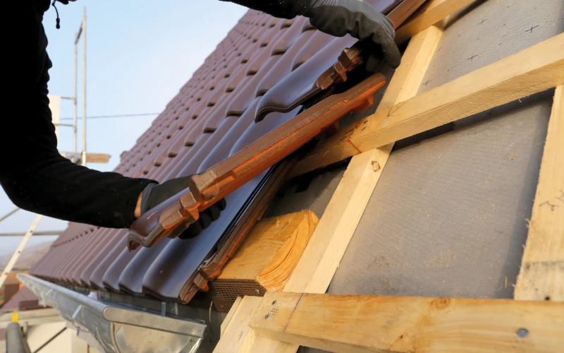 Dachdecker bringt Dachpfannen an Dachkonstruktion an