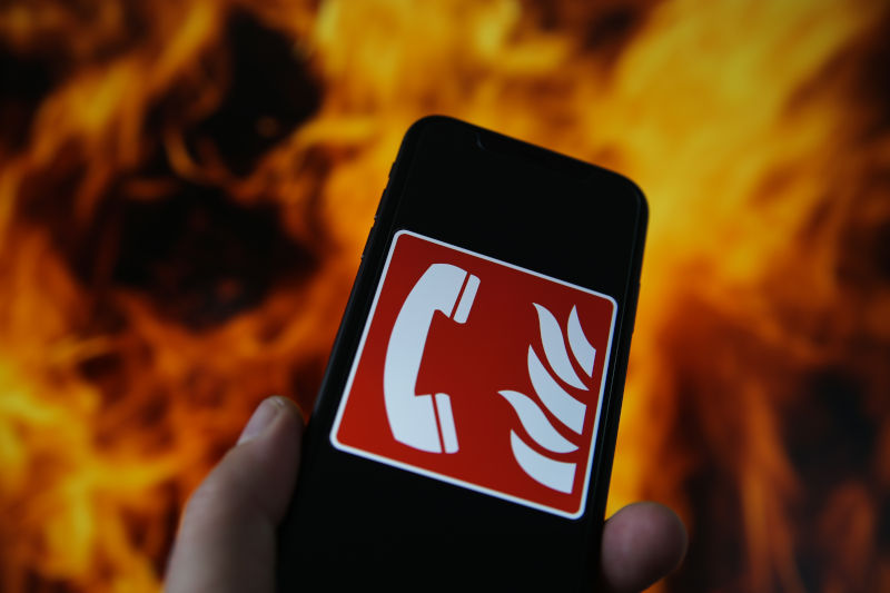 Sticker auf einem Handy mit Notruf vor Flammen