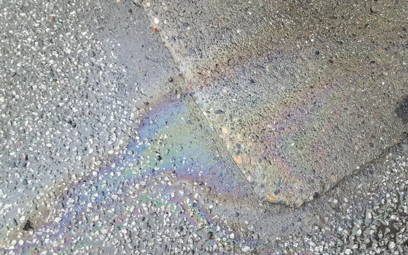 Ölfleck auf Asphalt. Eine Gefahr für Umwelt und rutschige Oberfläche.