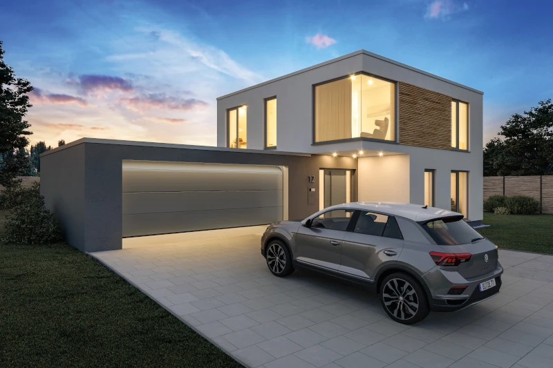 Ein Haus mit einer Garage in der Dämmerung. Die Lichter im Haus und in der Garage leuchten Hell. Ein Auto steht vor der Garage.