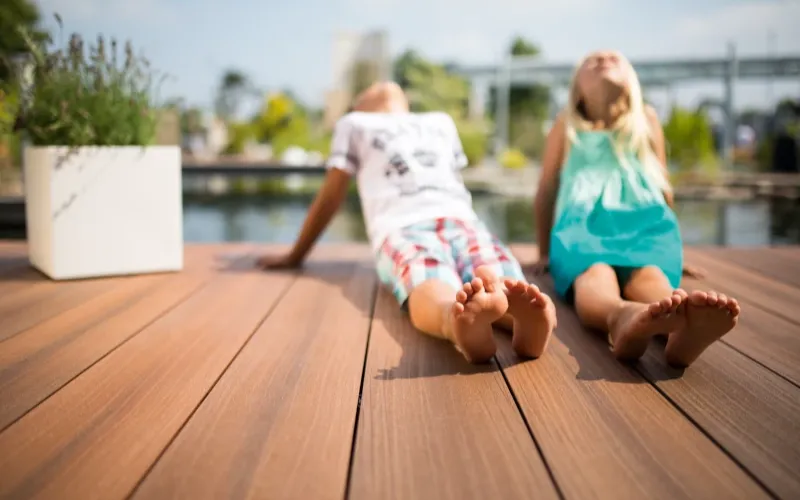 Pärchen sitzt auf braunen Terrassendielen auf GCC und genießt die Sonne
