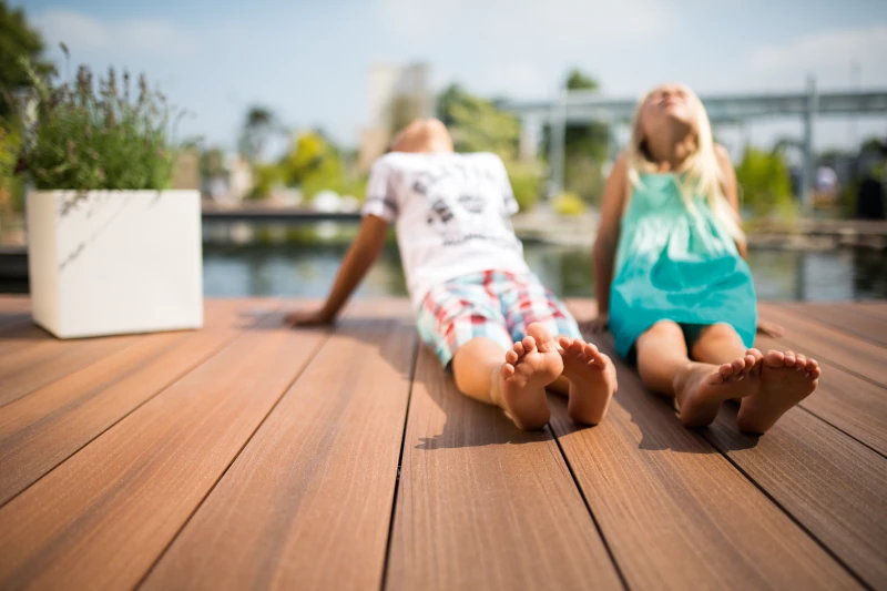 Pärchen sitzt auf braunen Terrassendielen auf GCC und genießt die Sonne