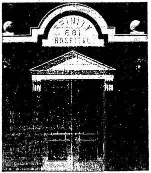 Black and white photo of a door with a pointed pediment and an arch reading Trinity 681 Hospital.
