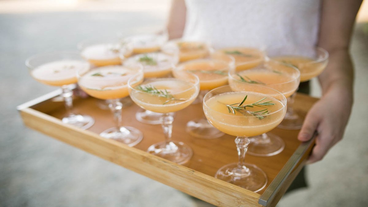 a tray of glasses containing orange colored refreshing summer cocktail