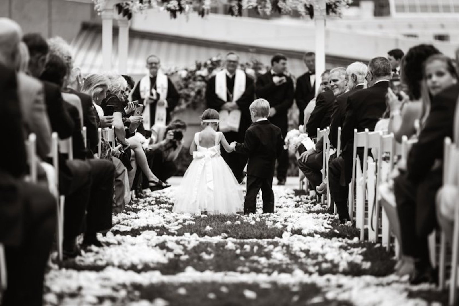 flower girl and ring bearer walking down flower covered aisle at wedding