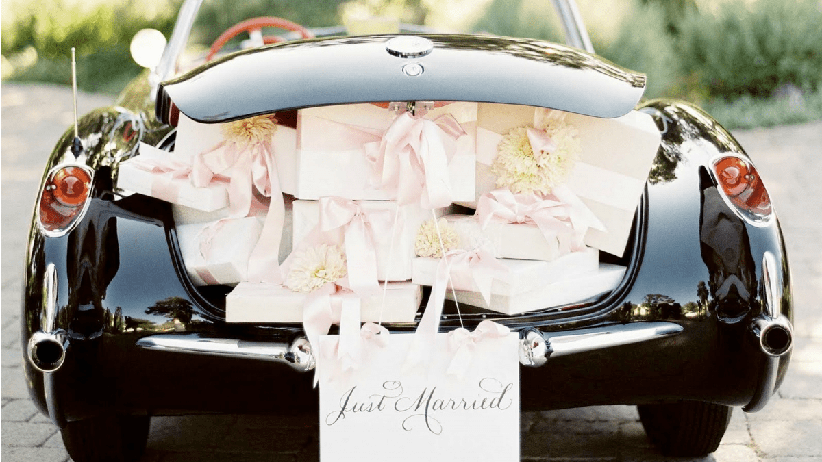 back view of black wedding car with open trunk loaded with wedding gifts and just married written on it