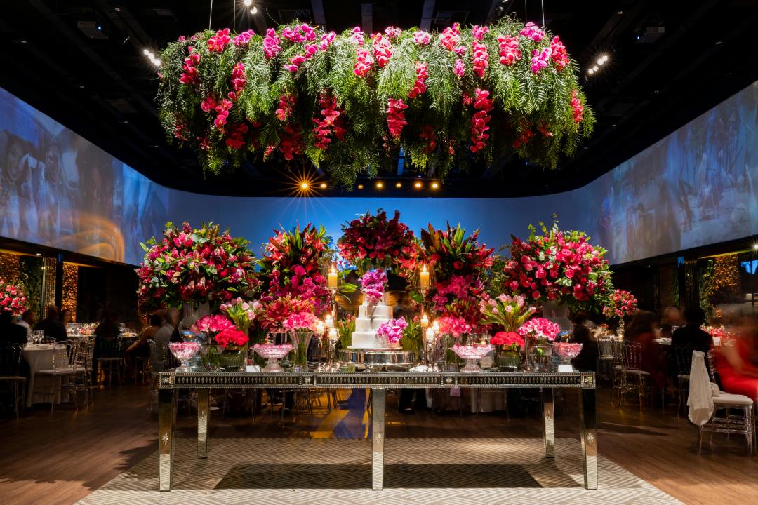 Wedding reception venue in jewel tones with a cake and explosion of flowers everywhere