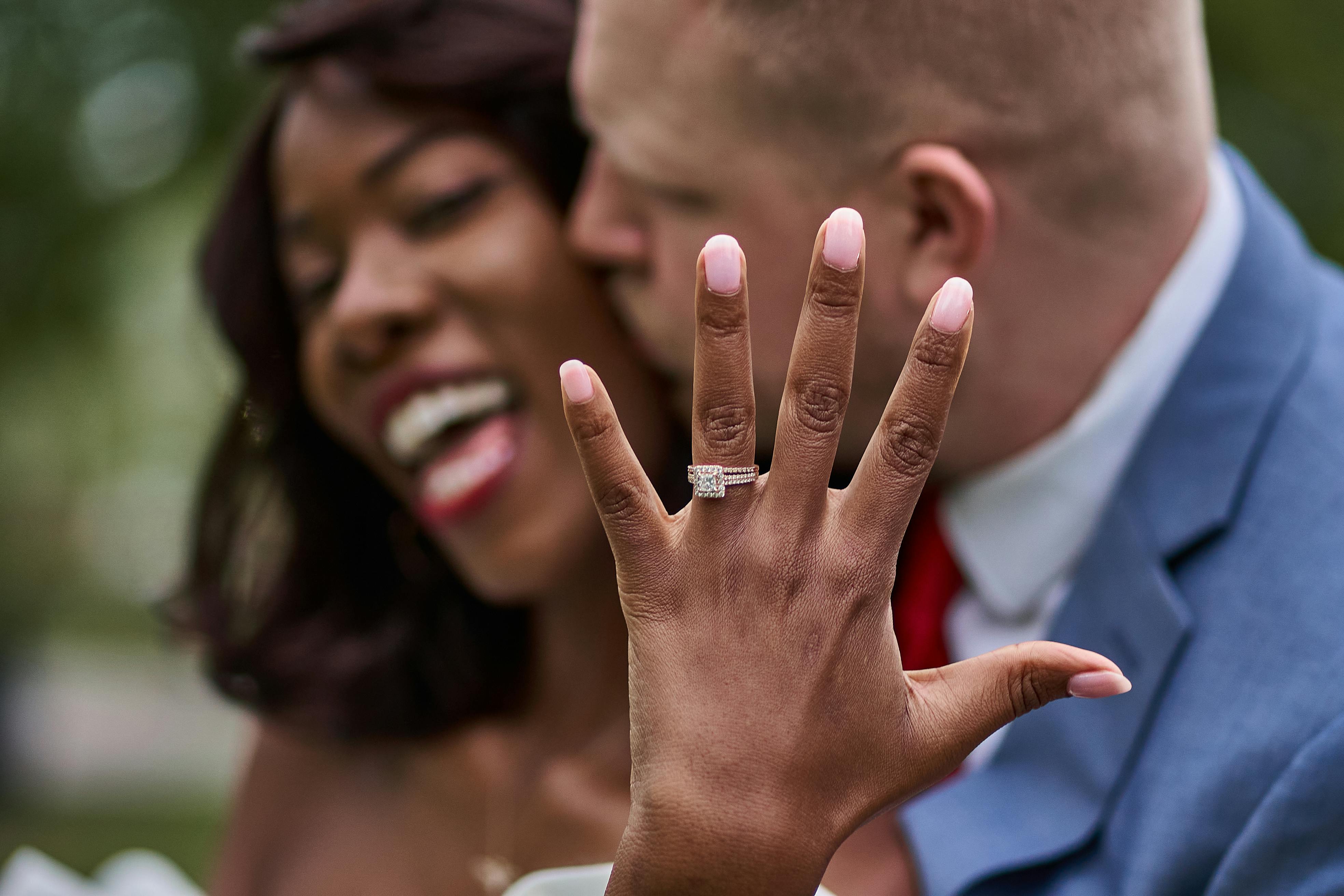 Woman show off her ring and her fiance kissing her on the cheek happily