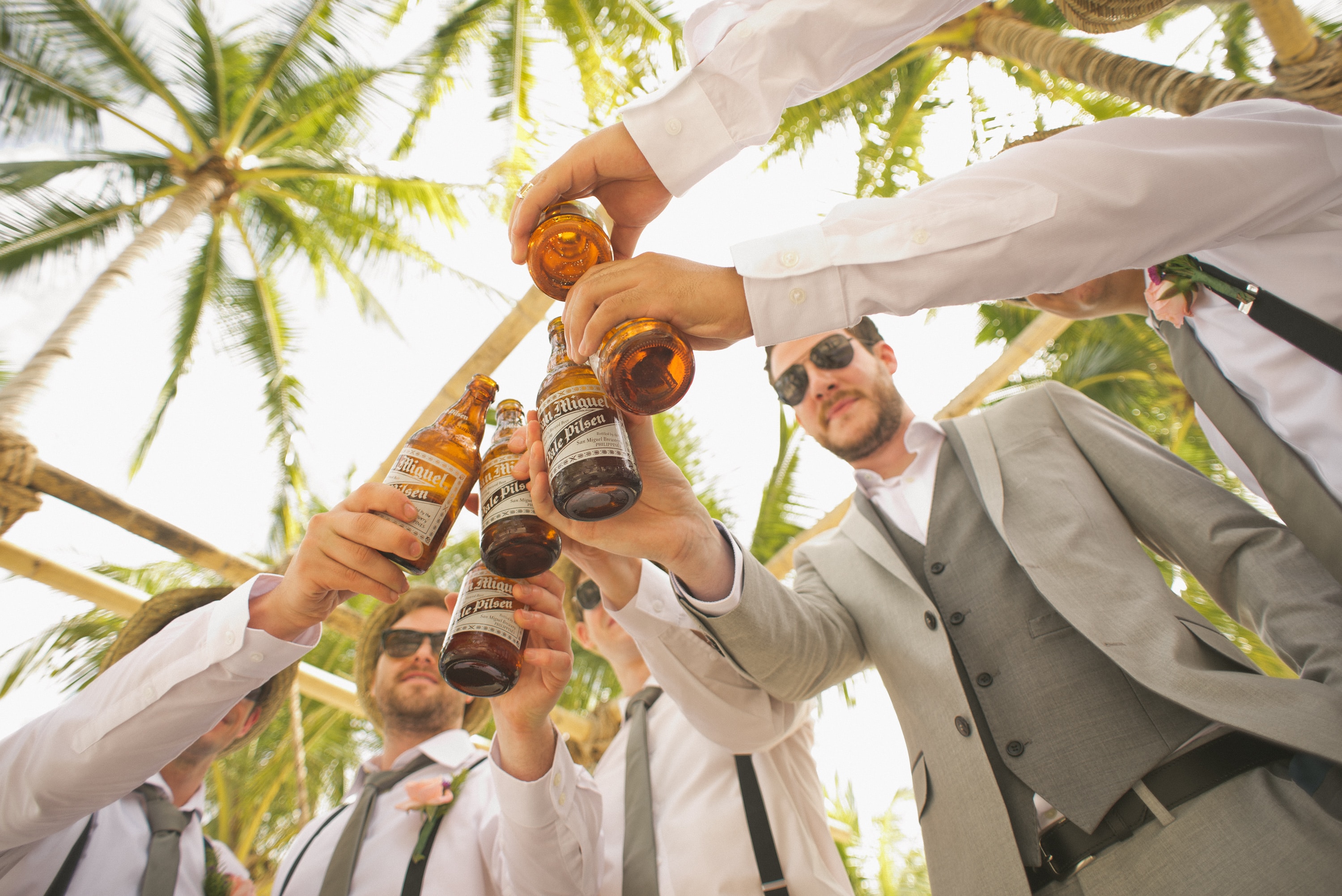 Low angle of groomsmen holding beer bottles and having a celebratory toast
